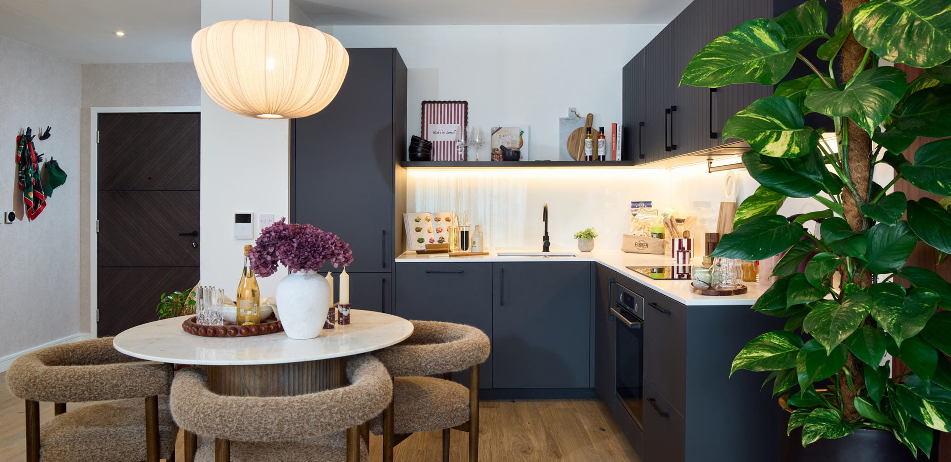 Kitchenette with slate grey colour palette, dining table and indoor plant