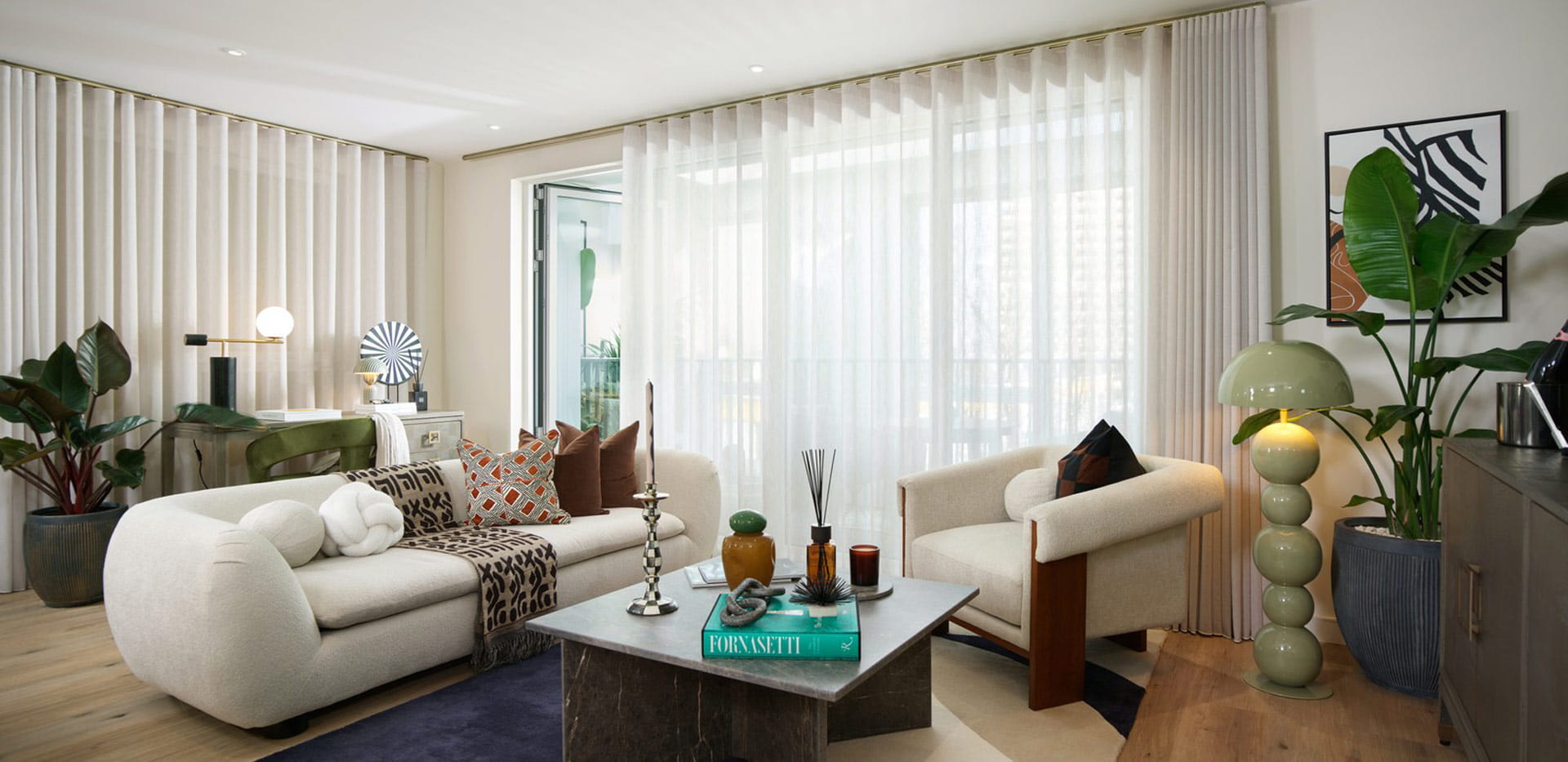 Modern designed living space with sofa and coffee table, ample natural lighting from wraparound tall windows.
