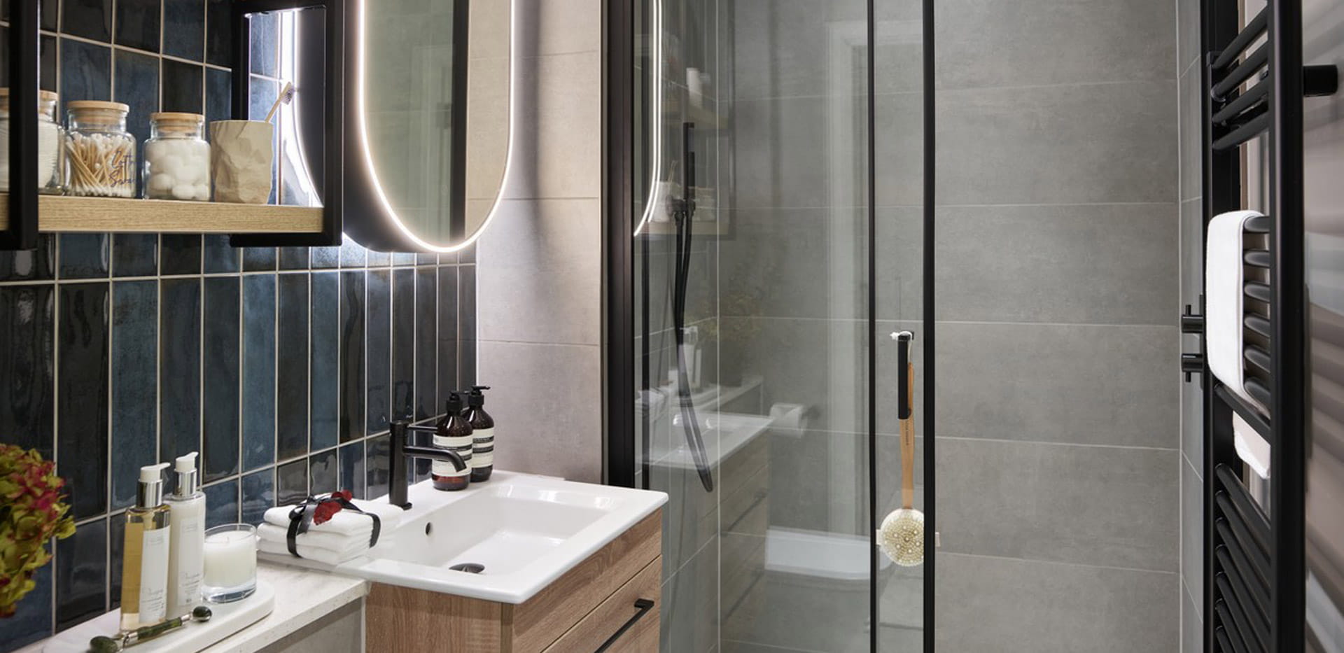 Modern designed shower unit, wash basin with wall mirror, heated towel rack, shelf space.