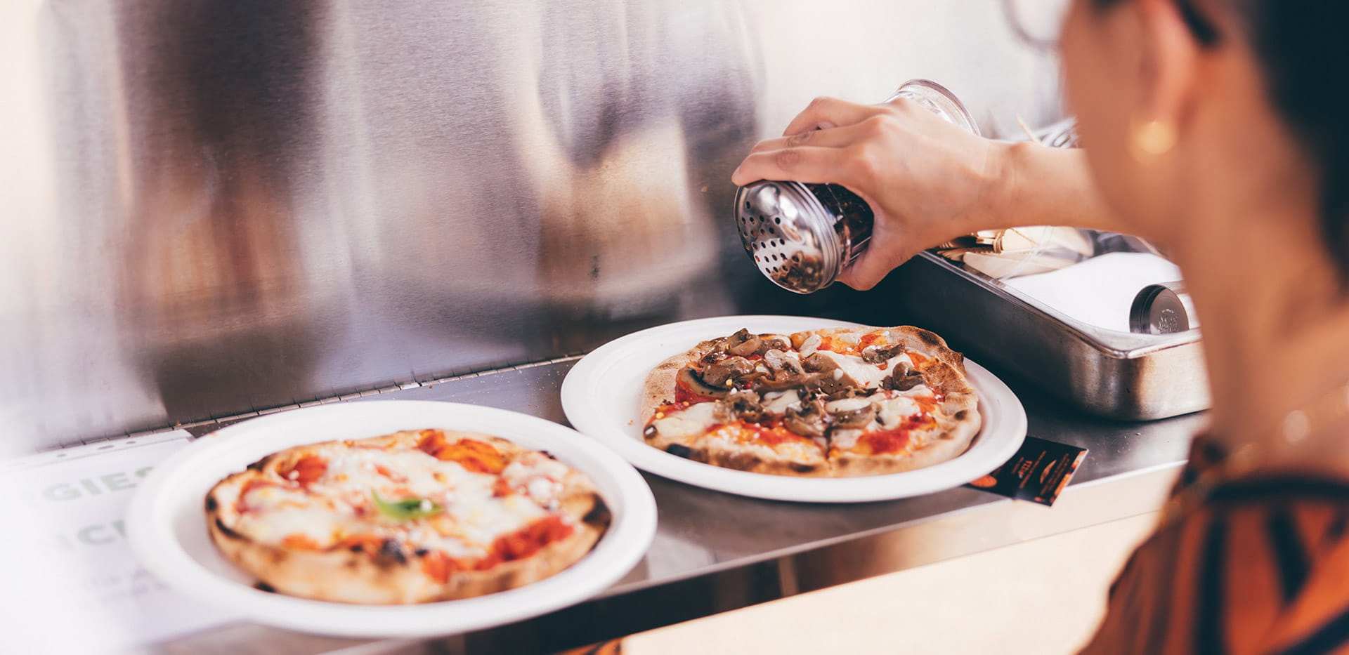 An image of a diner seasoning her pizzas at Parkside Yards