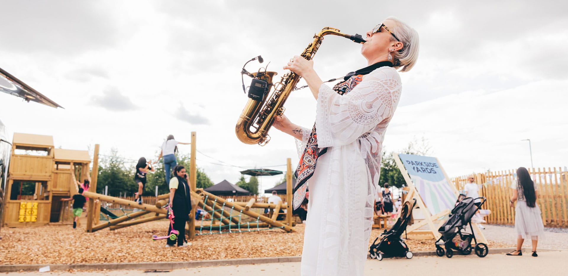 People enjoying a saxophone performer at Parkside Yards