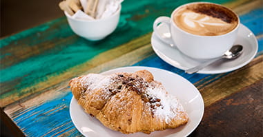 Closeup of a croissant with sugar dusting and a latte.