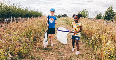 Two children with nets in tall grass.