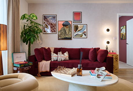 View of a modern designed living space with velvet sofa, coffee table, wall hangings and indoor plant.