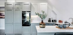 Kitchen area with light grey cupboards and white marble countertops 