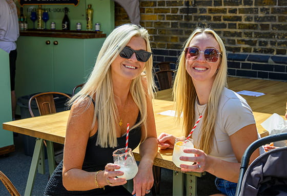 An image of two people enjoying drinks in the sun at Wandsworth Mills