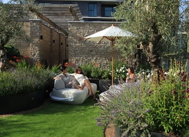 Outdoor garden seating area surrounded by lush green plants.
