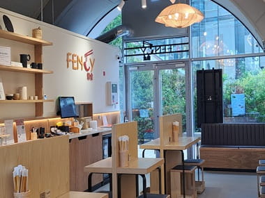 Interior restaurant view of Fency Noodles establishment: dining tables, counter, shop window.