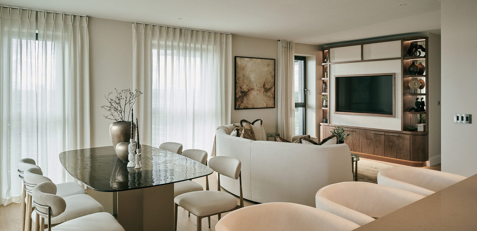 Closeup of breakfast island, glass dining table and living space in background.