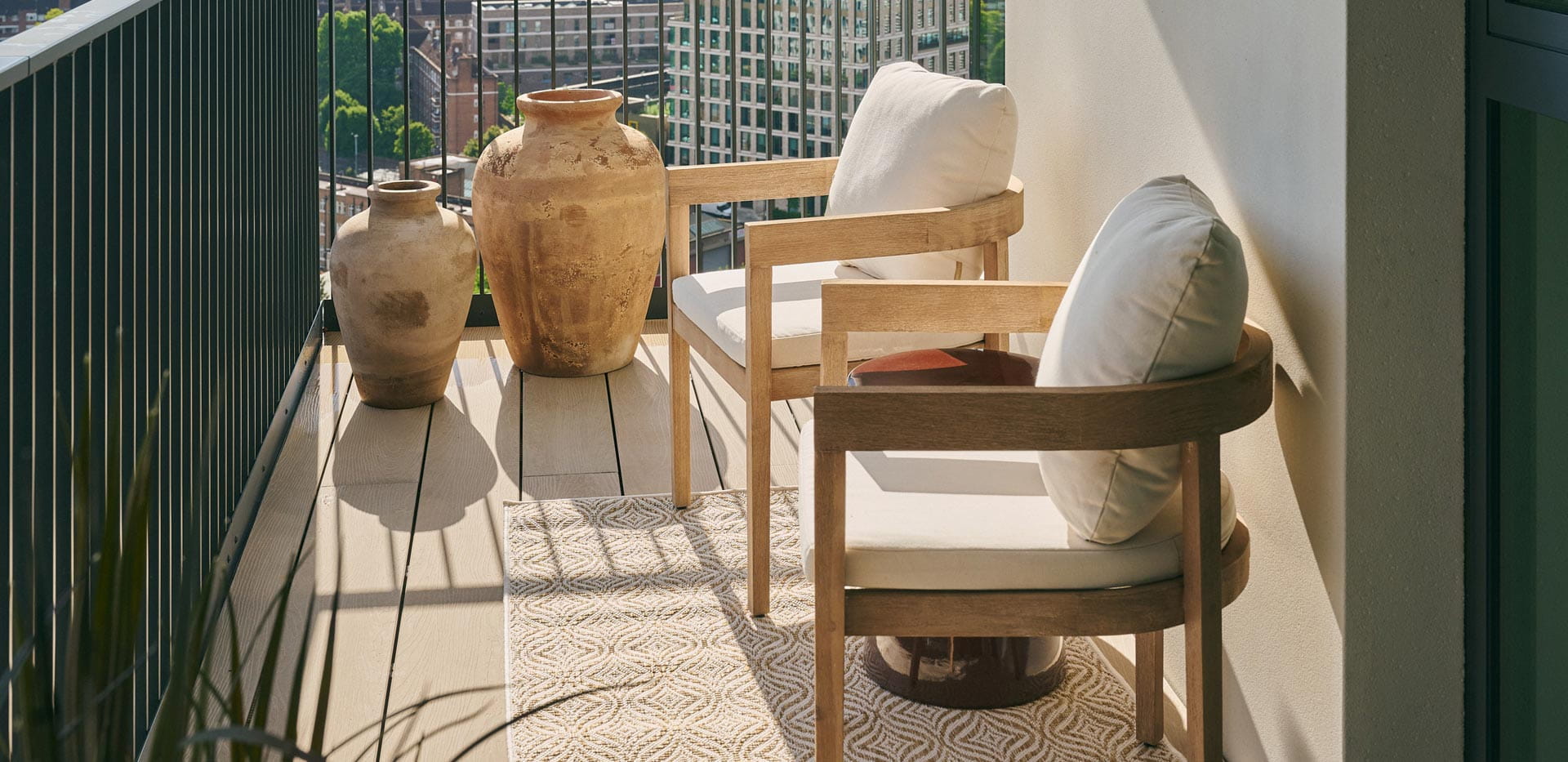 Closeup of balcony and outdoor furniture, overlooking city view.