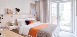 light coloured bedroom with white and orange bedding
