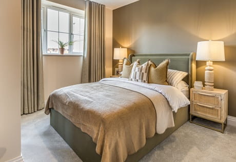 Double bed with bedside tables, carpet, décor is beige and light pink.