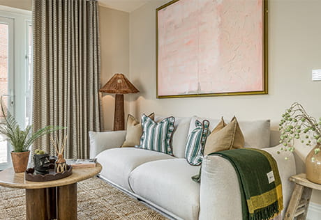Decorated interior living space: white fabric sofa against a beige wall with a wall hanging, light brown coffee table
