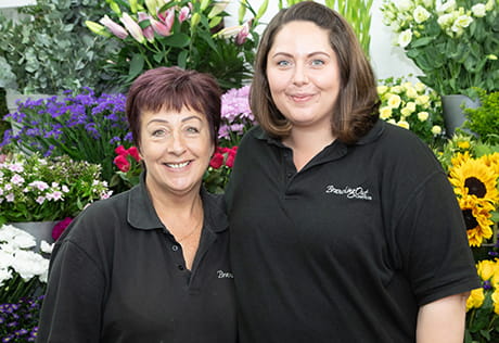 A picture of people standing in front of flowers