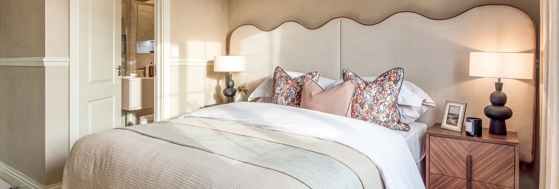 View of a doubled bed decorated in beige and cream, with wooden bedside tables