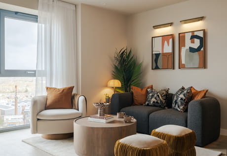 Modern designed living space with fabric two-seater sofa, stools, armchair and round coffee table