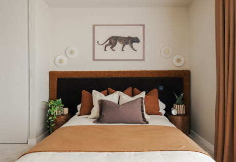 Made up bed with wall hanging, bedside tables, decorated in white-beige and gold-brown colour palette