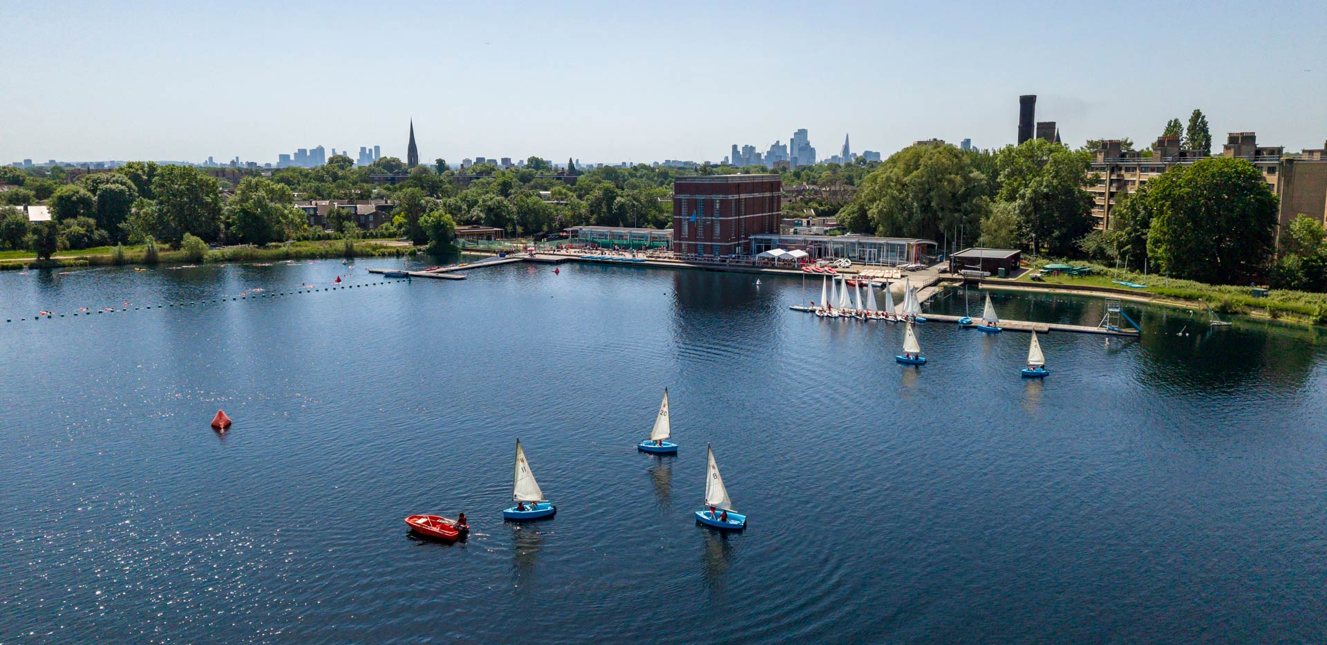 Sailboats on a body of water on a sunny day, viewed obliquely from the air.
