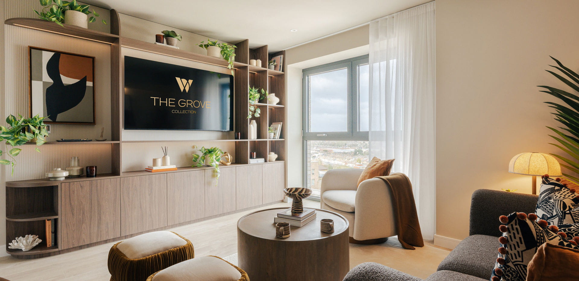 Modern designed and decorated living space with wall mounted TV and shelving unit, window and floor to ceiling curtains