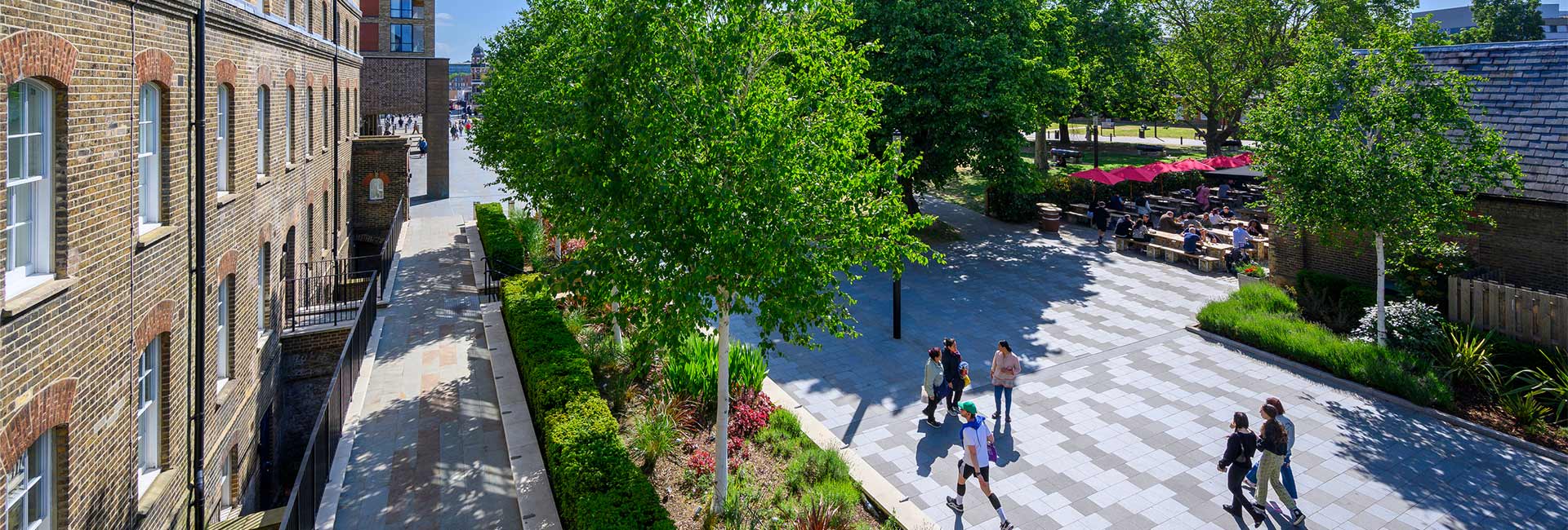 CGI of pedestrians walking along wide, tree-lined path, outdoor benches, modern buildings adjacent