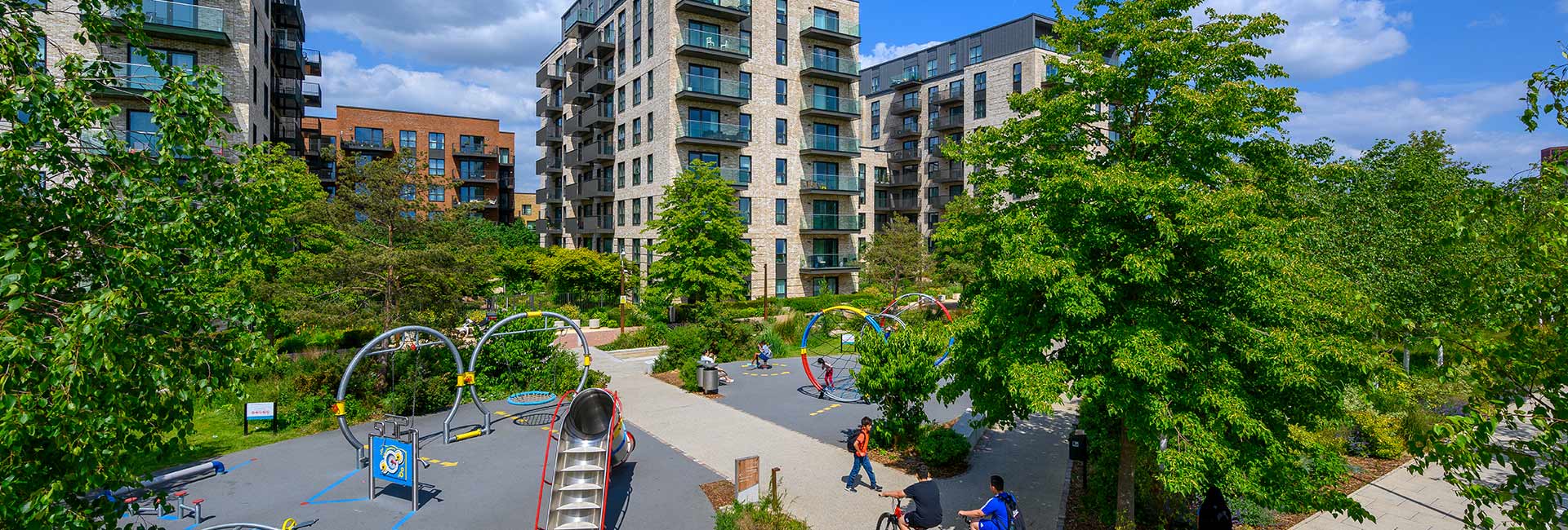 An exterior photograph of The Green Quarter showing a play park and apartment buildings