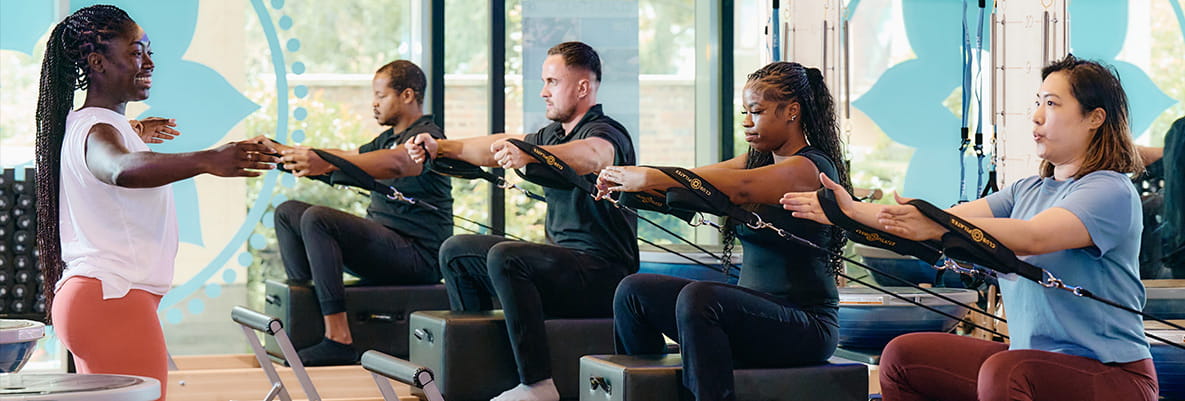 Master Pilates instructor Jada-Rae leading students through 'hug a tree' posture strengthening exercise using the reformer.