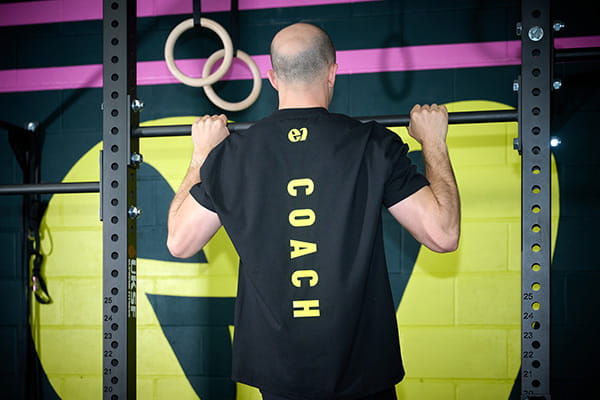 A coach at E1 Crossfit training by pulling himself up using a cross bar