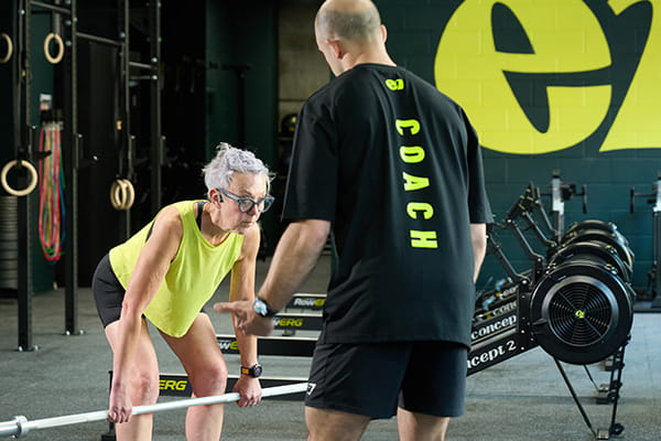 An E1 Crossfit coach training a woman with weights