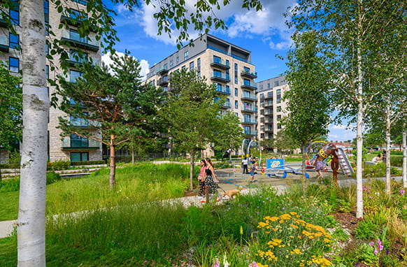A vibrant exterior image of The Green Quarter on a warm sunny day surrounded by green open space