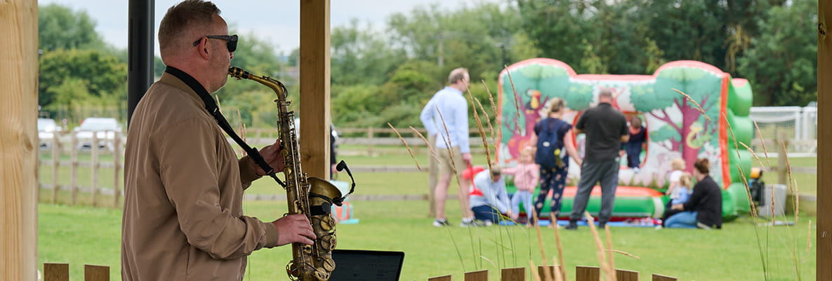 Image of a musician playing a saxophone at the Picnic in the Park event at Highcroft
