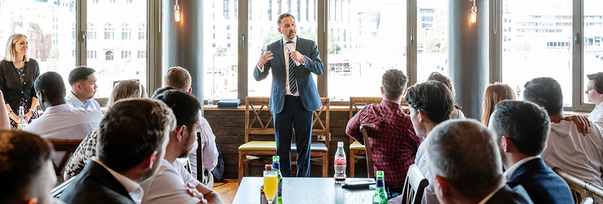 An image of all of the apprentices listening to someone talk