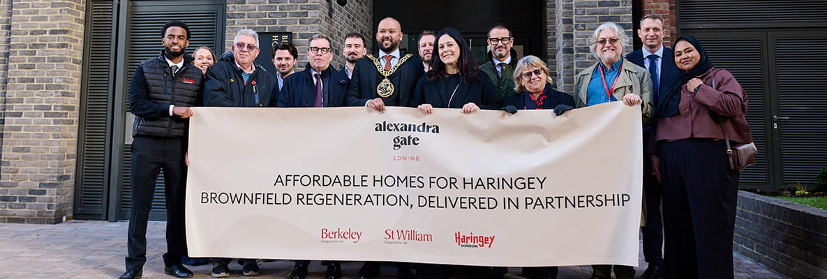 An image of people posing for a photo holding a large banner on affordable homes