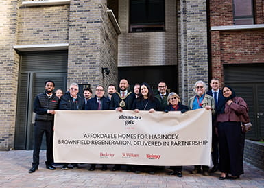 An image of people posing for a photo holding a large banner on affordable homes