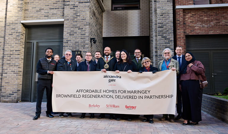 An image of people posing for a photo holding a large banner on affordable homes