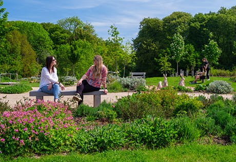 An exterior image of people on a bench surrounded by Green Space