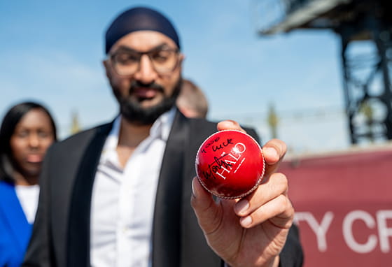 A person holding a signed cricket ball