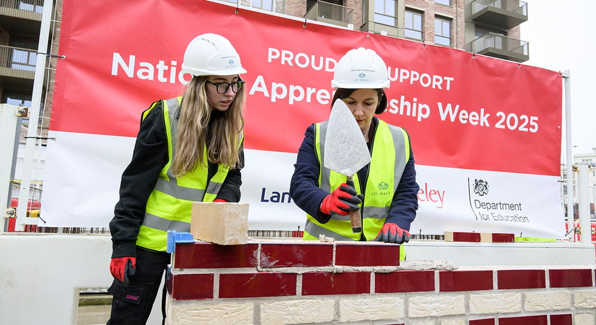 An image of the Secretary of State for Education trying brick work with a Berkeley Staff member