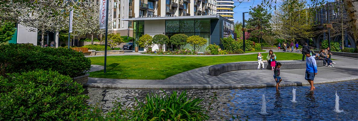Water feature in foreground with new build apartment buildings in background.