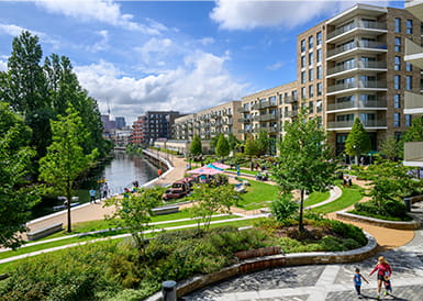 CGI of sunlight streaming through green landscaped playground with new build apartments in background.
