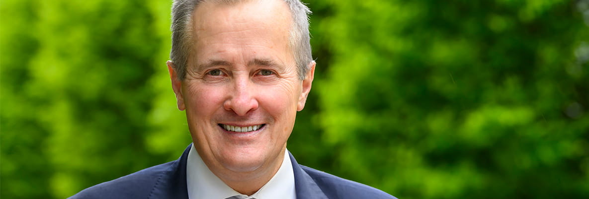 A headshot image of Rob Perrins with greenery in the background