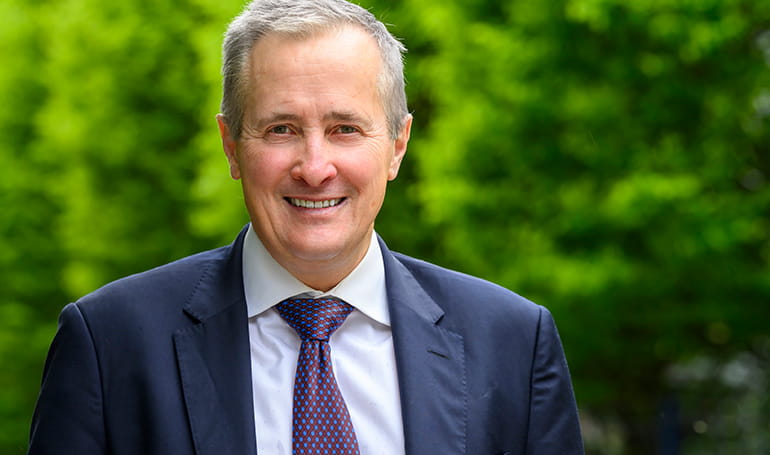 A headshot image of Rob Perrins with greenery in the background